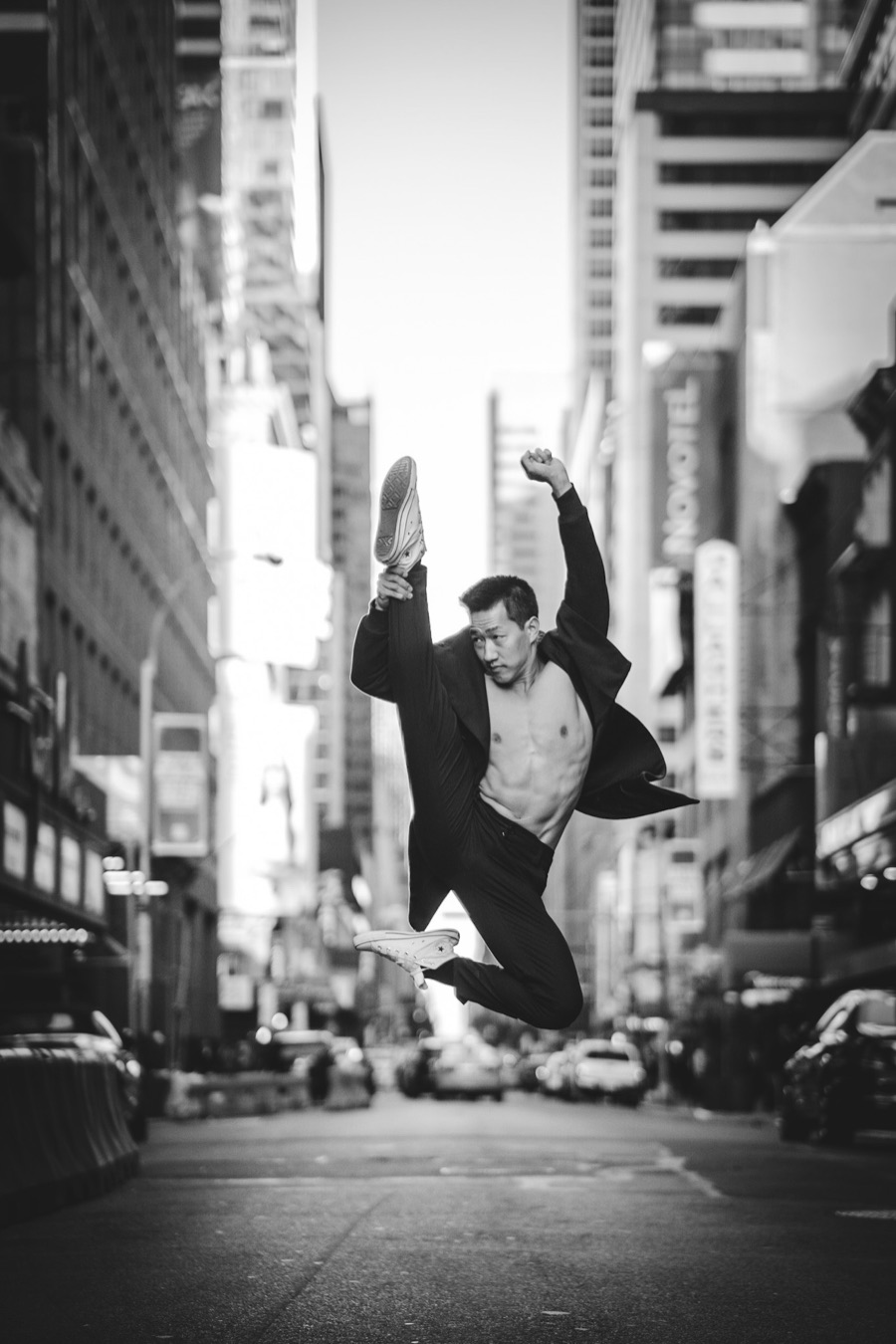 Black-and-white photo of Alex Wong leaping on a New York street