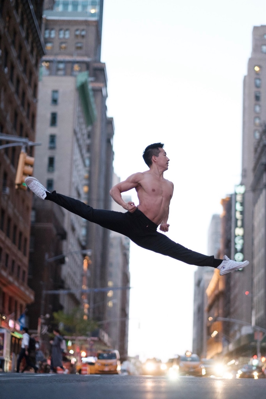 Alex Wong in a shirtless split leap between Manhattan towers