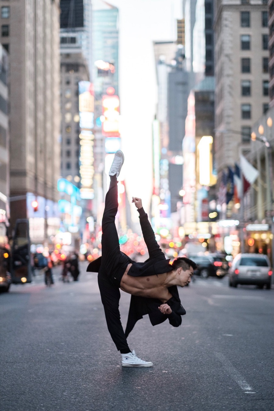 Alex Wong kicking one leg straight up on a Midtown street