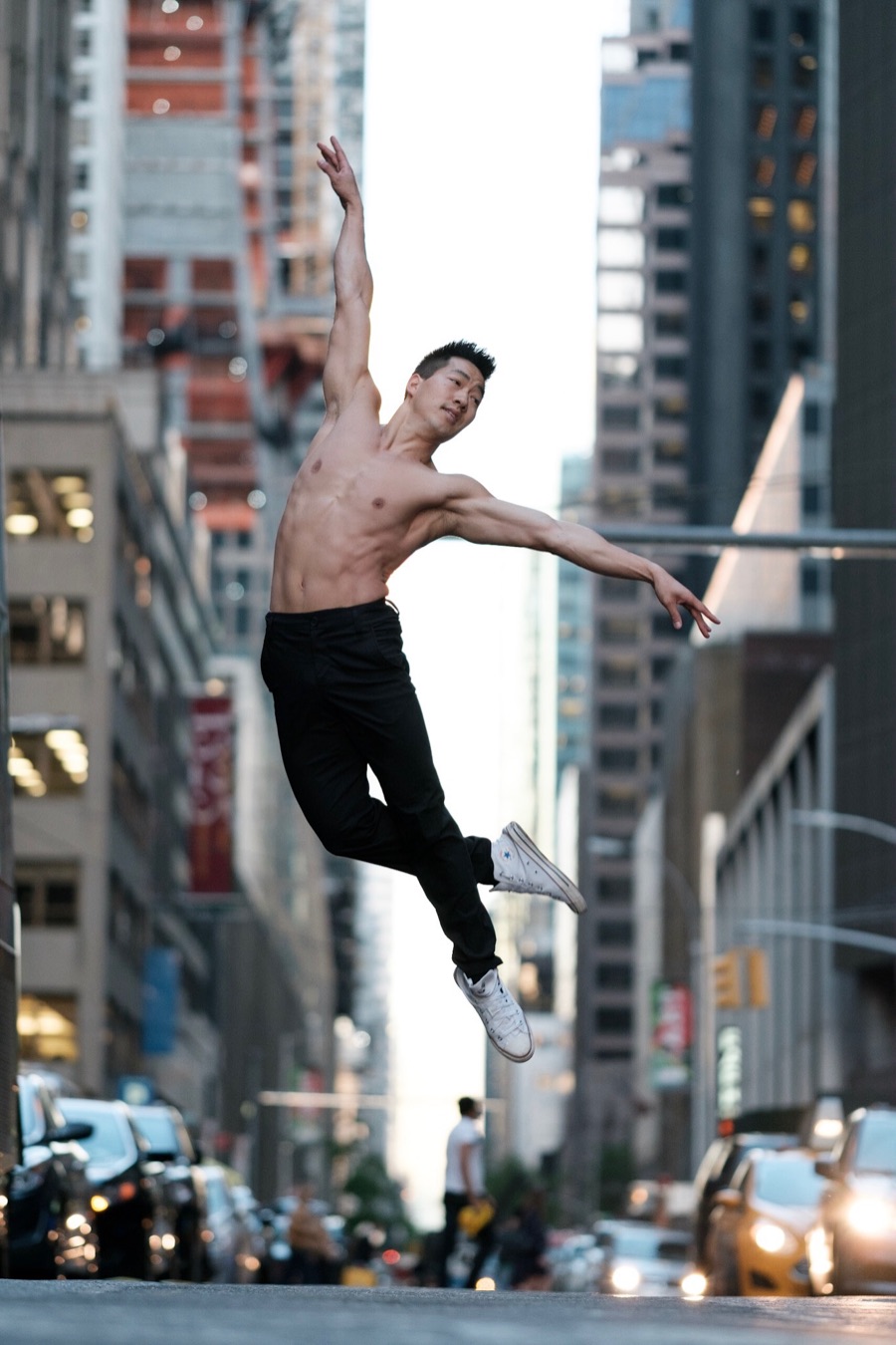 Alex Wong in an arched, shirtless leap on a Manhattan street