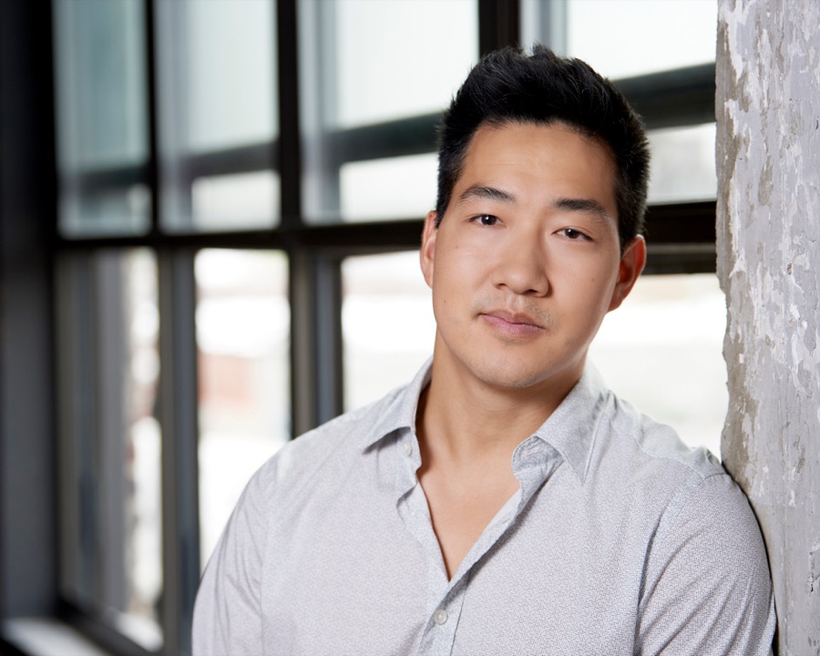 Portrait of Alex Wong in a white shirt by a loft window