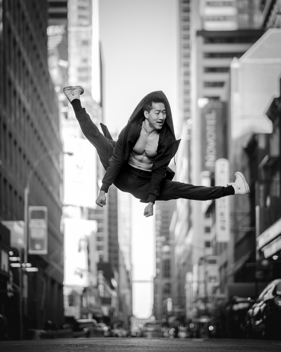 Black-and-white photo of Alex Wong mid-leap on a Midtown street