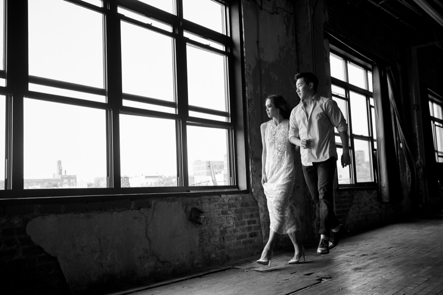 Black-and-white photo of Alex Wong walking with a woman past loft windows