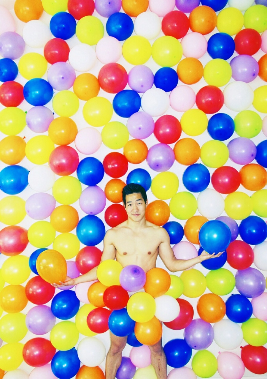 Alex Wong lying in a pool of colourful balloons