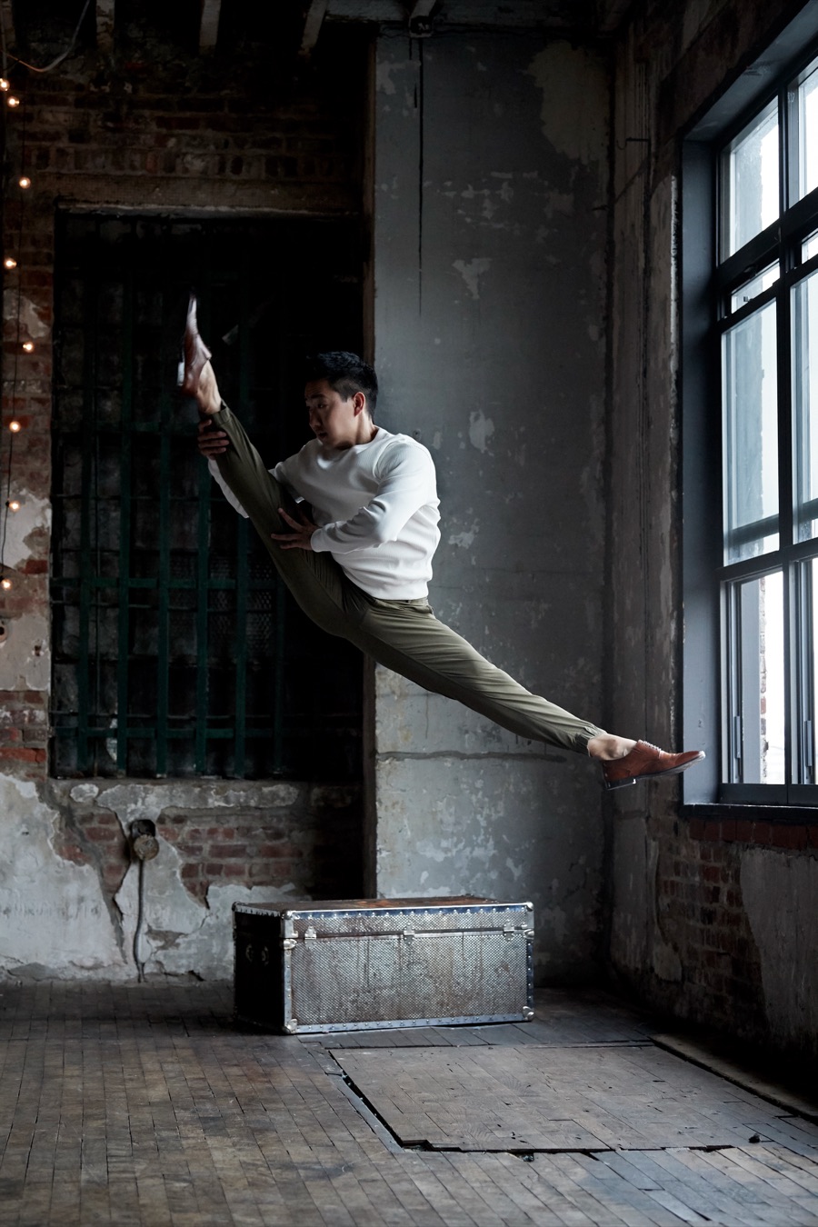 Alex Wong in a split leap across a brick loft studio