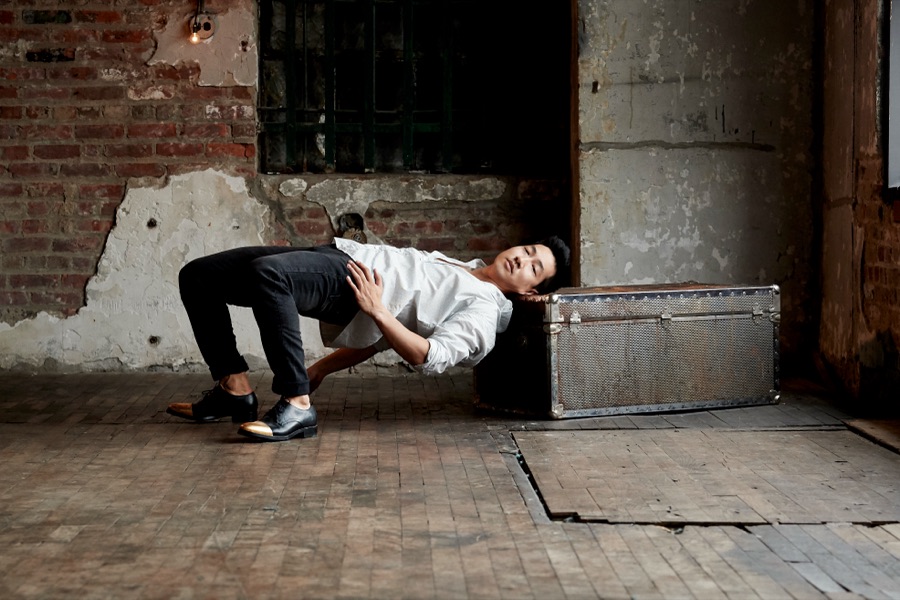 Alex Wong arching backwards over a metal trunk