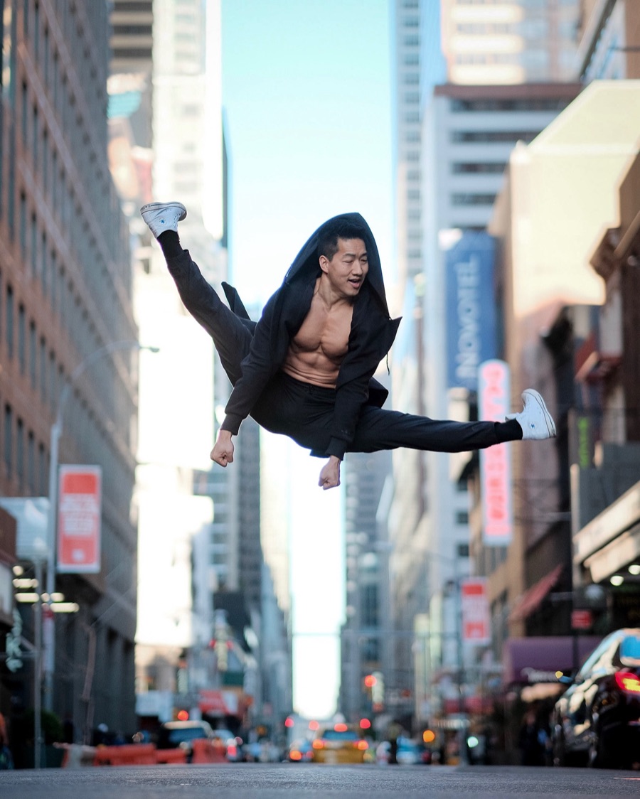 Alex Wong mid-leap in a hooded jacket on a Midtown Manhattan street