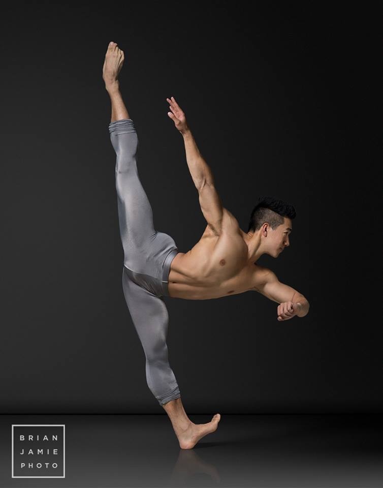 Alex Wong in a high arabesque against a dark backdrop