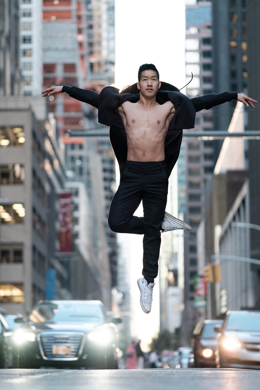 Alex Wong jumping with arms spread wide in the middle of a city street