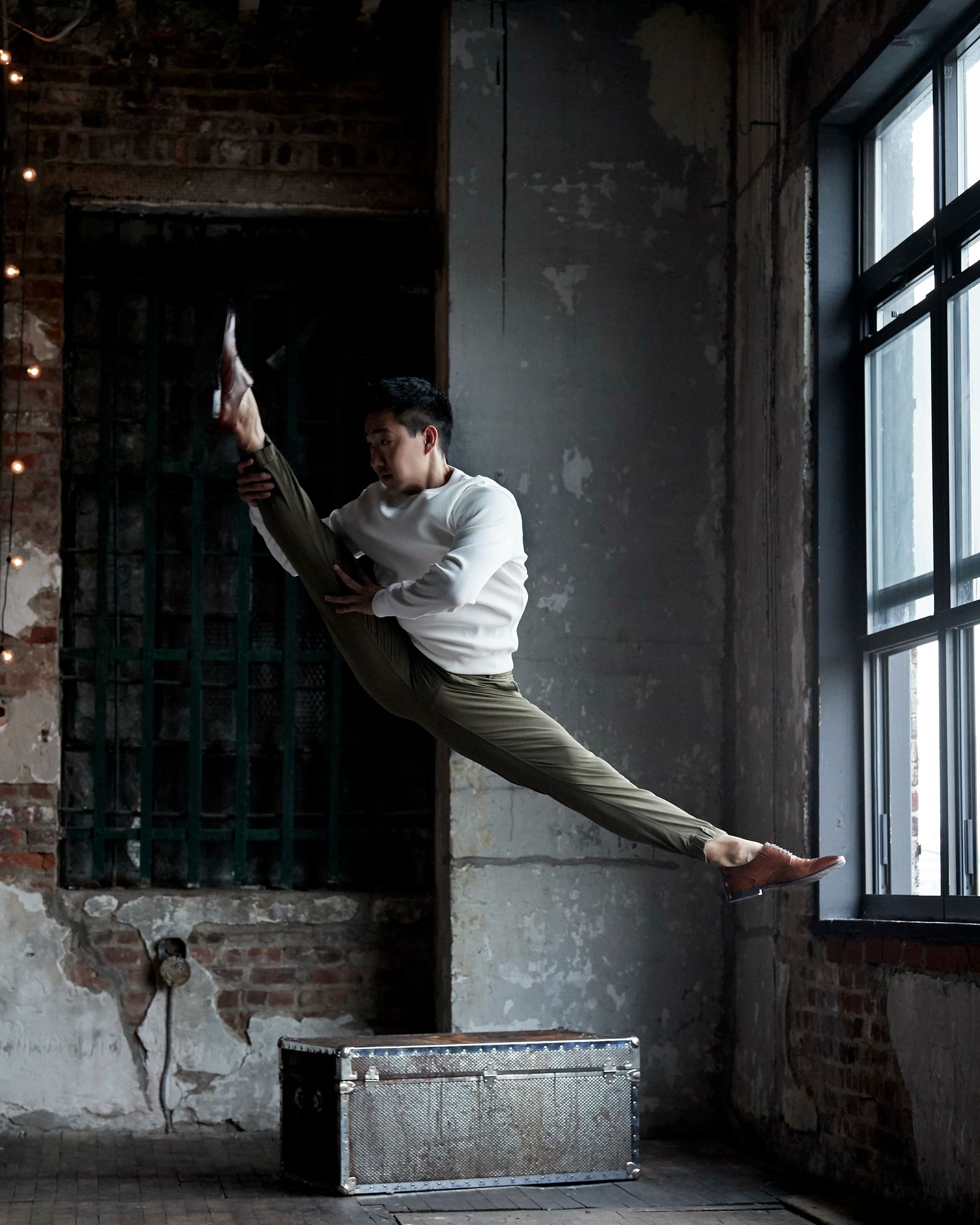 Alex Wong in a split leap across a brick loft studio